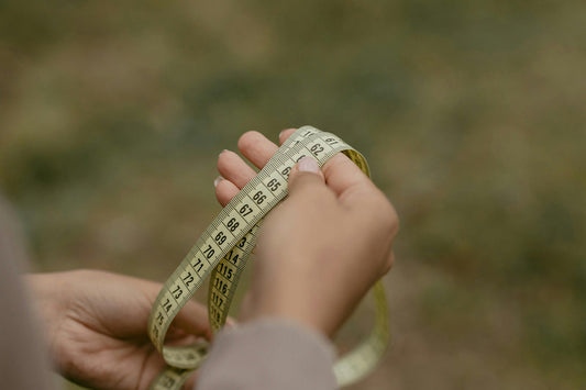 A lady showing inches tape to measure size of kids.